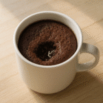 Keto mug cake in white mug on light wood counter