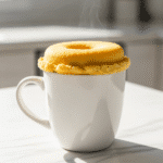 Fresh microwave mug donut in white ceramic mug ready to eat