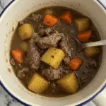 Beef stew in a mug ready to serve in terracotta ceramic mug with steam rising