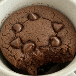Chocolate chip mug cookie freshly microwaved in terracotta ceramic mug with gooey melted chocolate chips
