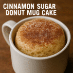 Fluffy cinnamon sugar donut mug cake in white ceramic mug with golden brown top and cinnamon coating from BusyCookLife kitchen