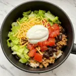 Taco Bowl in a Mug with seasoned ground beef, rice, melted cheese and fresh toppings - BusyCookLife trusted recipe